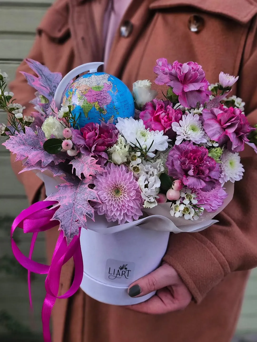 Rozā un violeta ziedu kompozīcija baltā kastītē ar mazu globusu